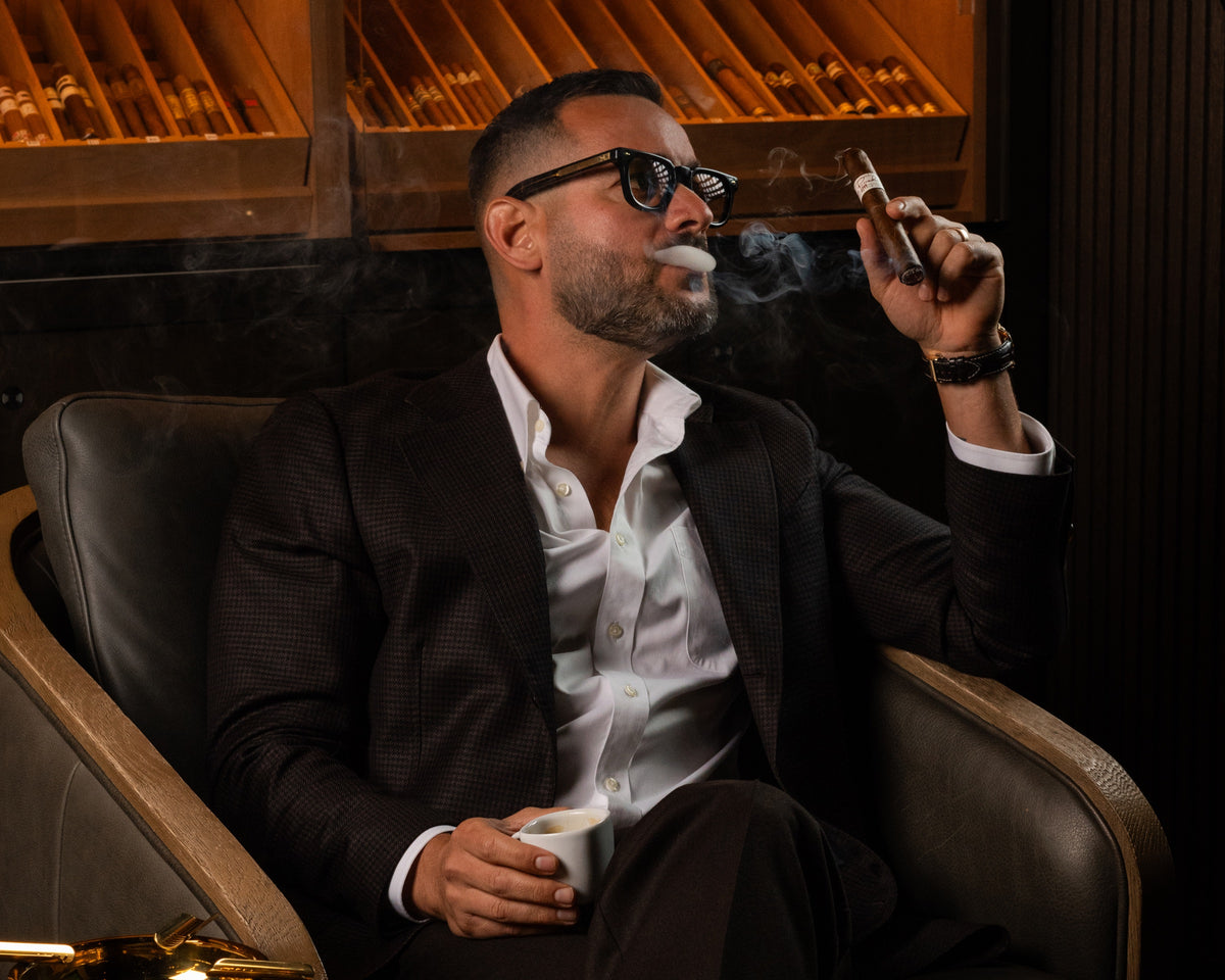 Guest smoking a cigar and holding a drink in the Cigar Club Miami lounge